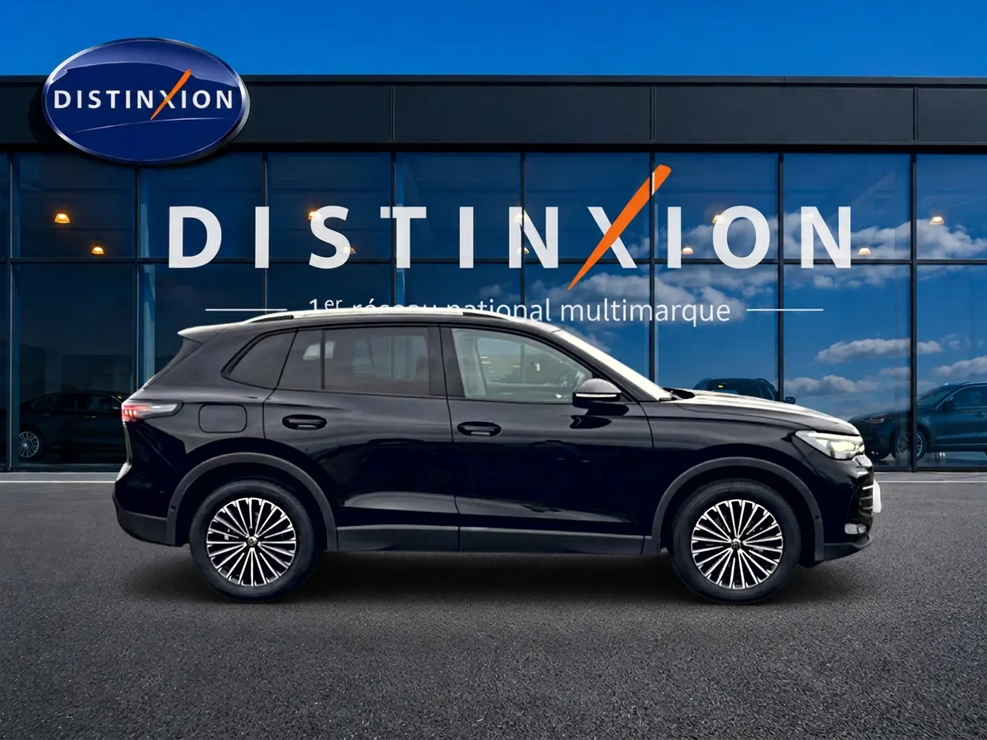 Volkswagen Tiguan noir en profil droit devant une vitrine avec logo Distinxion, jantes stylisées visibles.