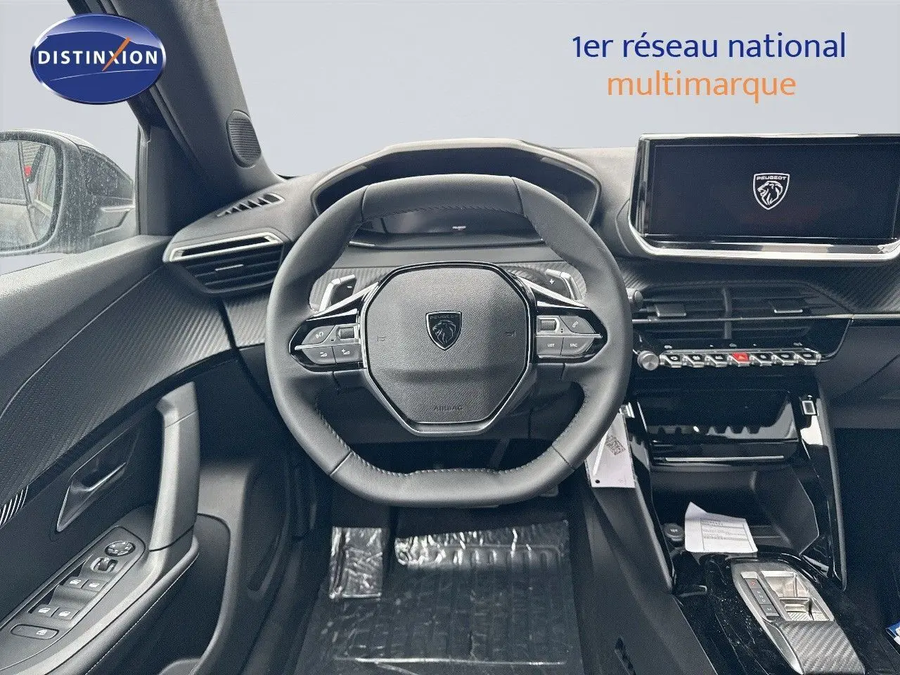 Vue intérieure centrée sur le volant et tableau de bord du Peugeot 2008 Hybrid noir métal avec écran tactile et finitions carbone.