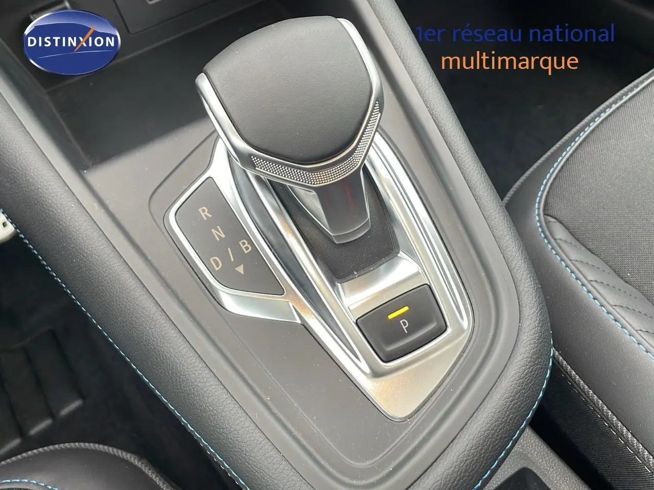 Le levier de vitesses automatique de la Renault SYMBIOZ gris rafale, avec surpiqûres bleues et bouton parking éclairé.