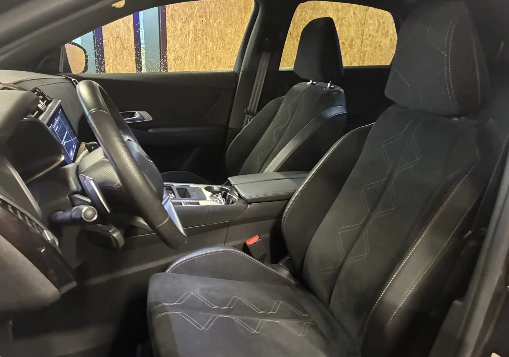 Vue intérieure côté conducteur du DS7 E-TENSE 2024, sièges noirs en alcantara avec surpiqûres et tableau de bord moderne.