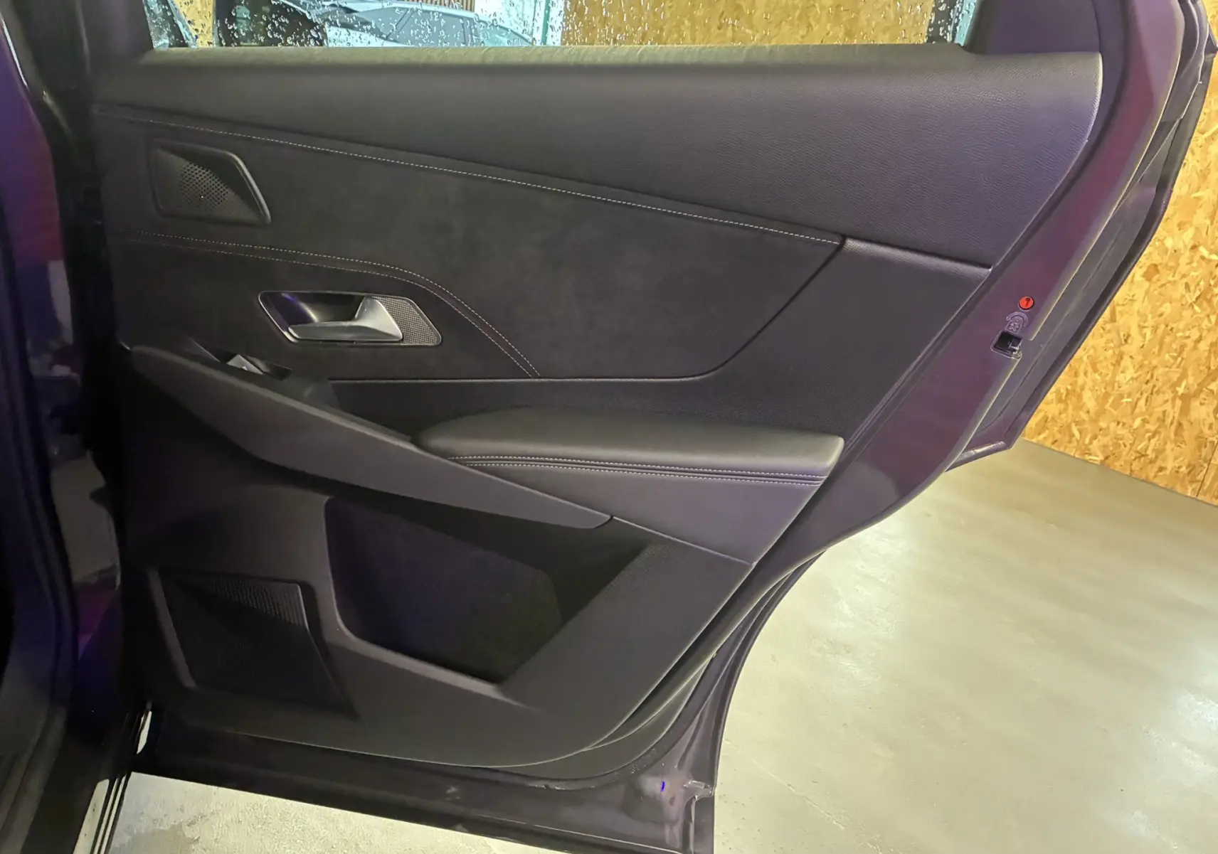 Vue intérieure de la porte arrière droite du DS7 E-TENSE 2024 en gris, avec garniture noire et surpiqûres contrastées.