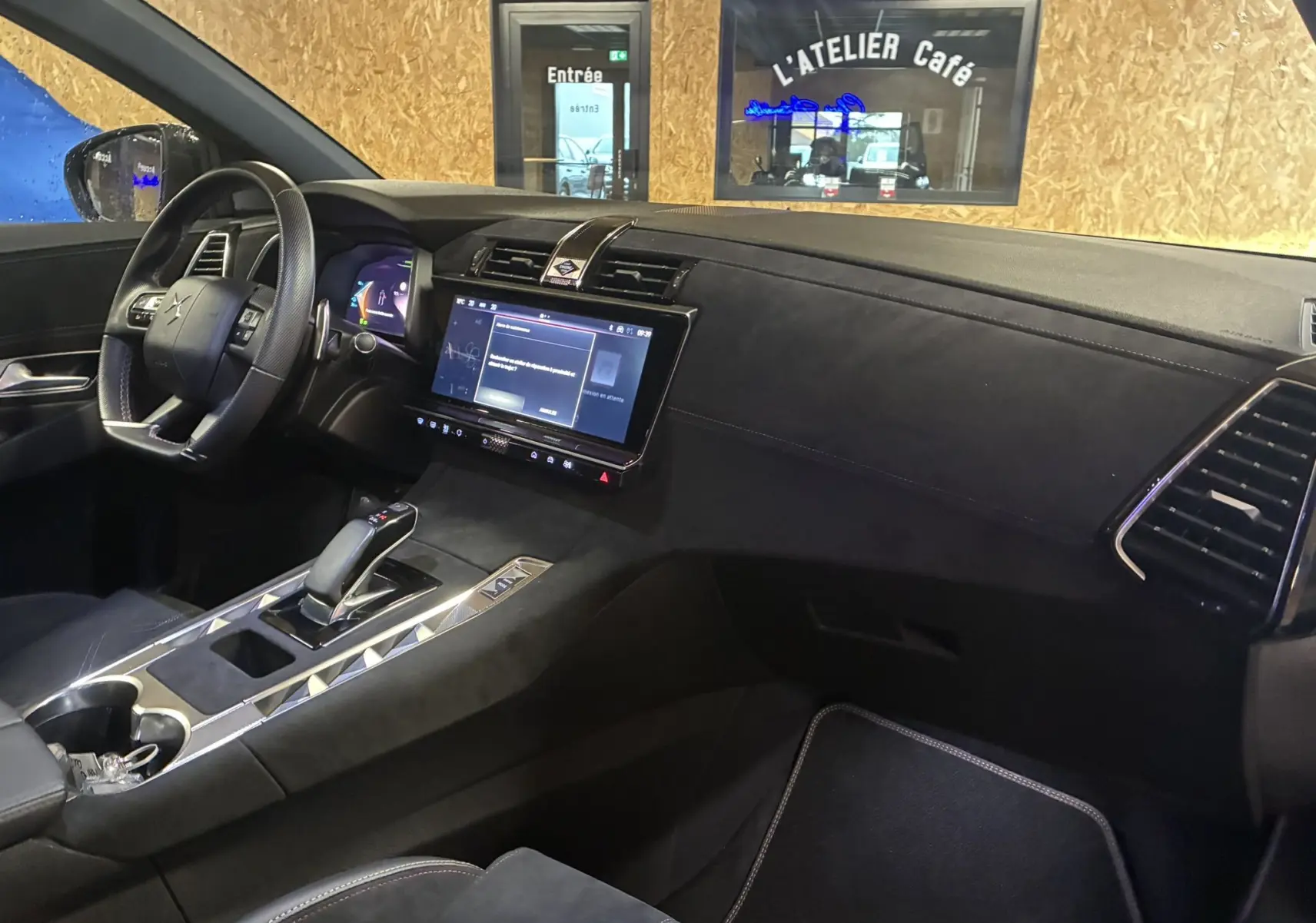 Intérieur noir du DS7 E-TENSE 2024 vu côté passager, avec tableau de bord épuré et écran tactile central allumé.