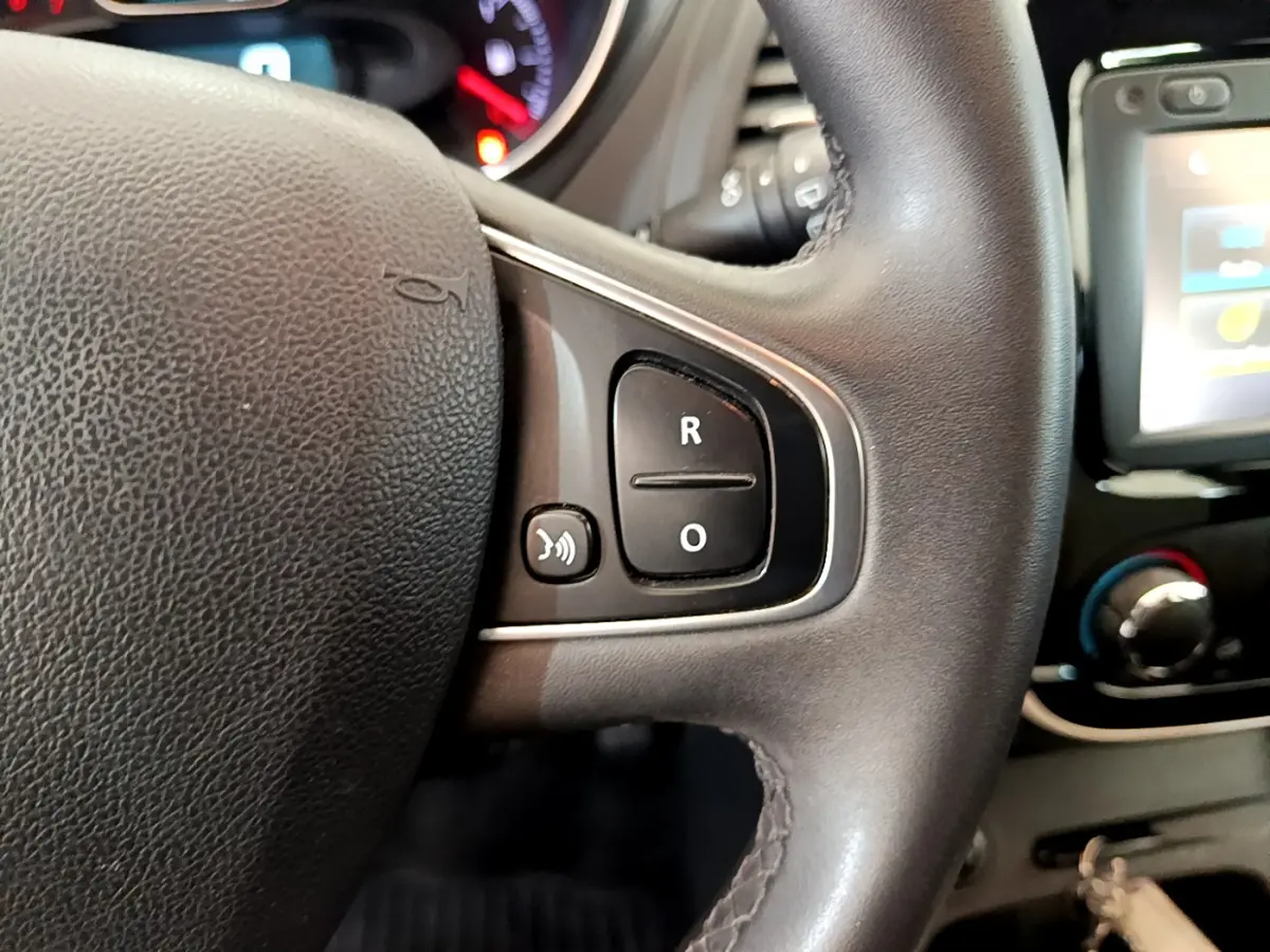 Gros plan sur le volant cuir multifonctions du Renault Captur gris foncé, avec commandes vocales et écran tactile visible.