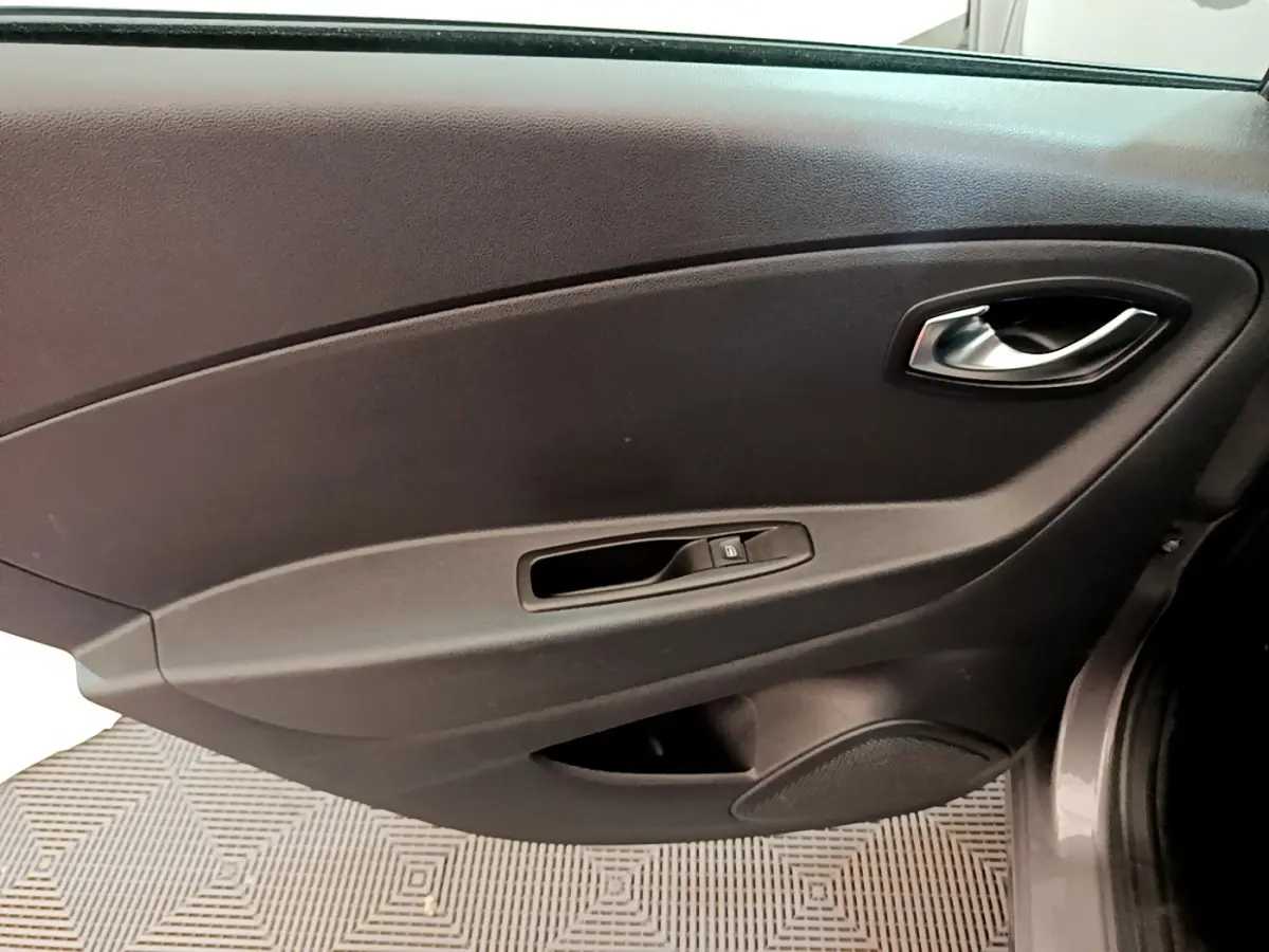Vue rapprochée de la porte intérieure côté droit du Renault Captur gris foncé, avec poignée et commande de vitre électrique.