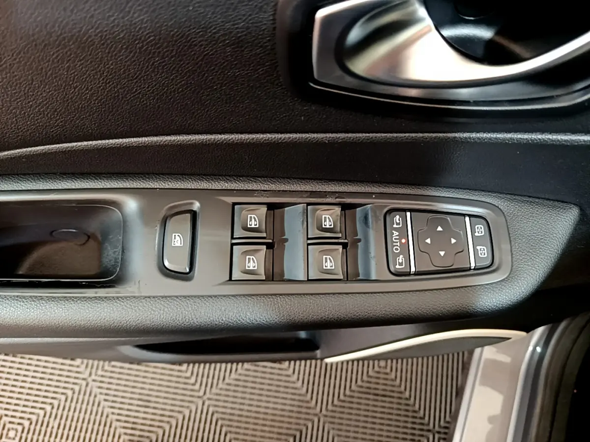 Vue rapprochée du panneau de commandes des vitres et rétroviseurs côté conducteur d’un Renault Captur gris foncé.