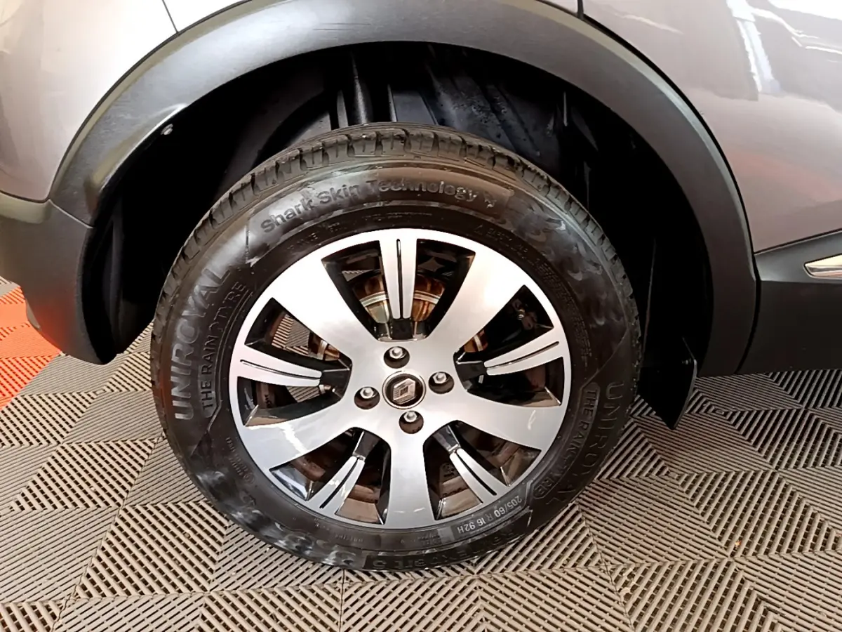 Gros plan sur la roue avant gauche du Renault Captur gris foncé, mettant en valeur la jante alliage et le logo central.