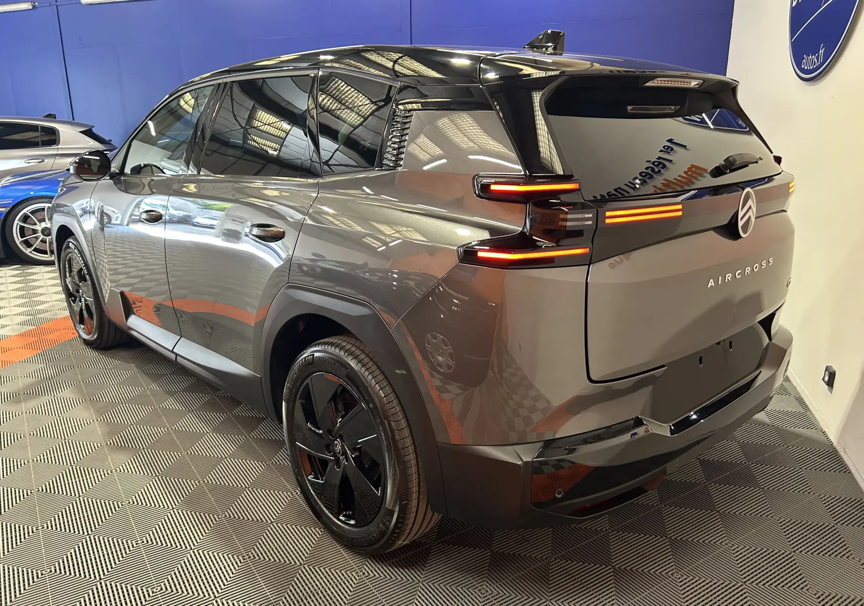 Vue 3/4 arrière droite du Citroën C5 Aircross gris Platinium avec toit noir et feux arrière allumés en intérieur.