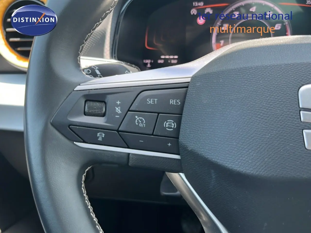 Gros plan sur le volant cuir noir du SEAT Arona 2025, montrant les commandes multifonctions côté gauche.
