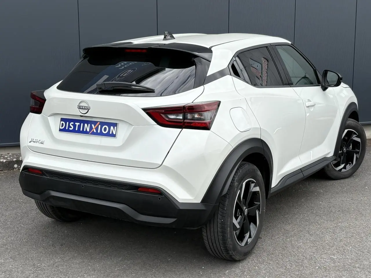 Nissan Juke blanc perle vu en 3/4 arrière droit, avec jantes alliage noires et vitres arrière teintées.