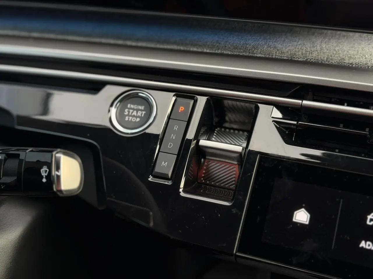 Gros plan sur la console centrale noire brillante du Peugeot 3008 Hybrid avec bouton start/stop et commandes de boîte auto.