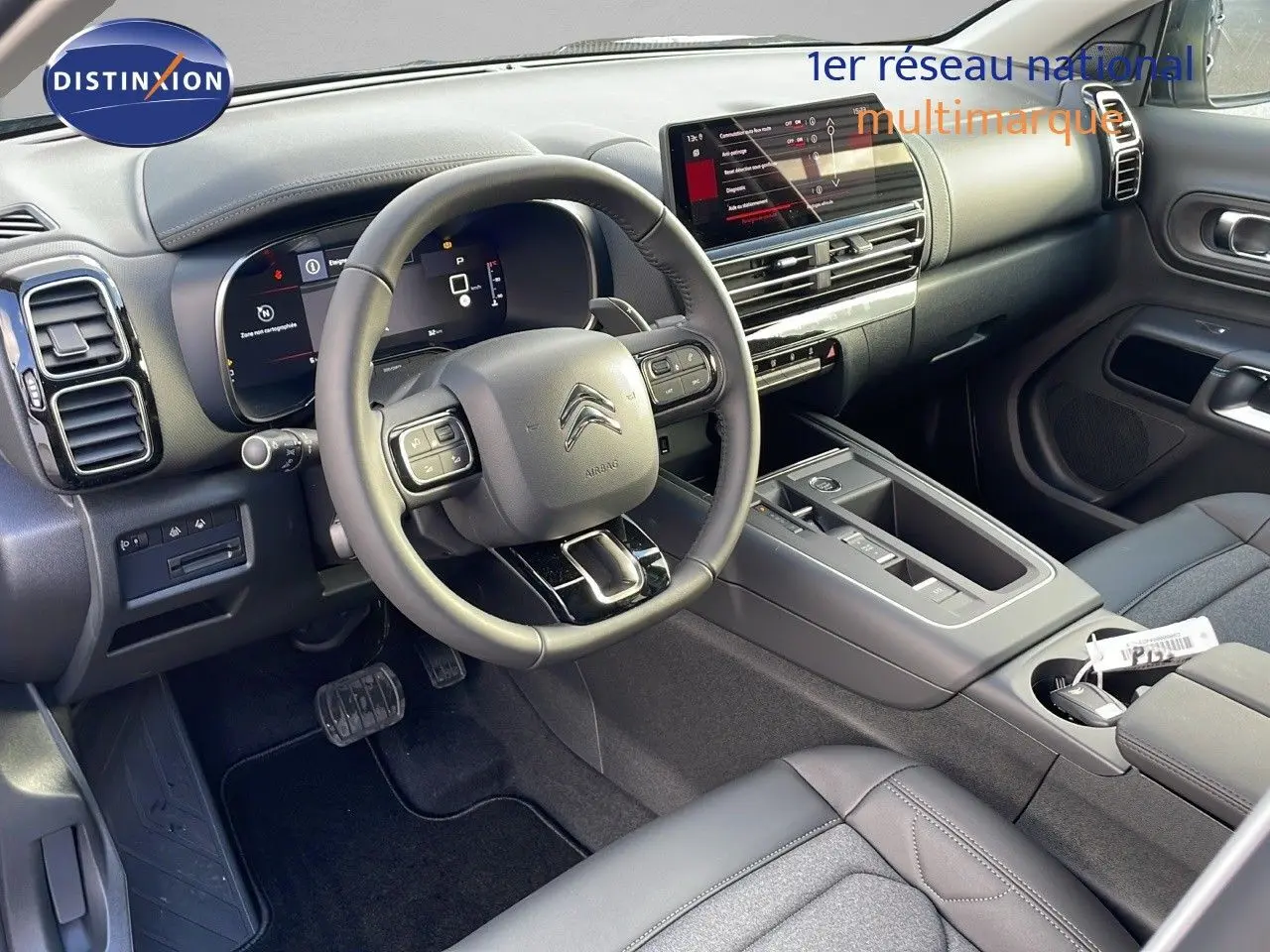 Vue intérieure côté conducteur du Citroën C5 Aircross 2025, tableau de bord moderne avec écran tactile et volant cuir noir.