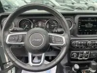 Vue intérieure du tableau de bord et volant Jeep Wrangler Unlimited 2023, avec écran tactile et commandes au volant visibles.