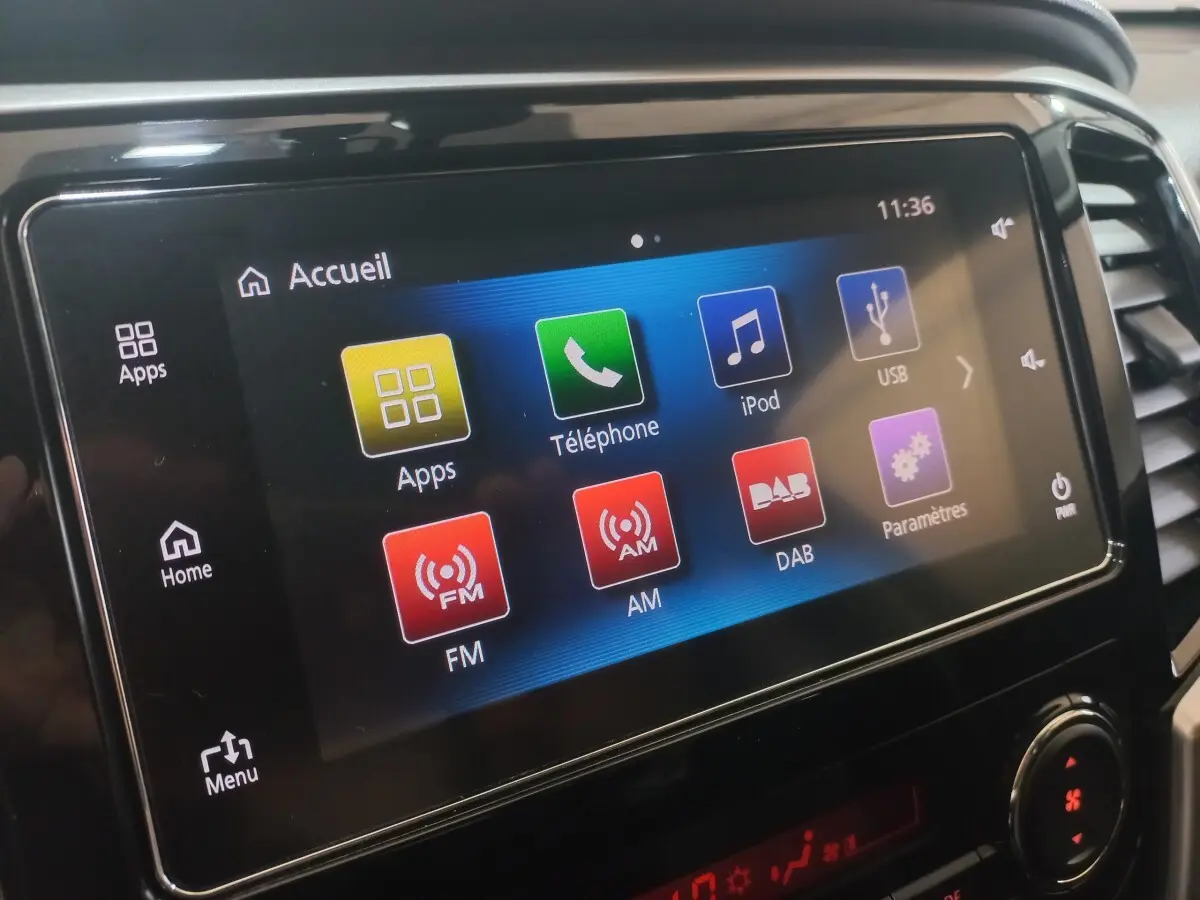 Écran tactile central du tableau de bord du Mitsubishi L200 gris foncé, affichant le menu multimédia.