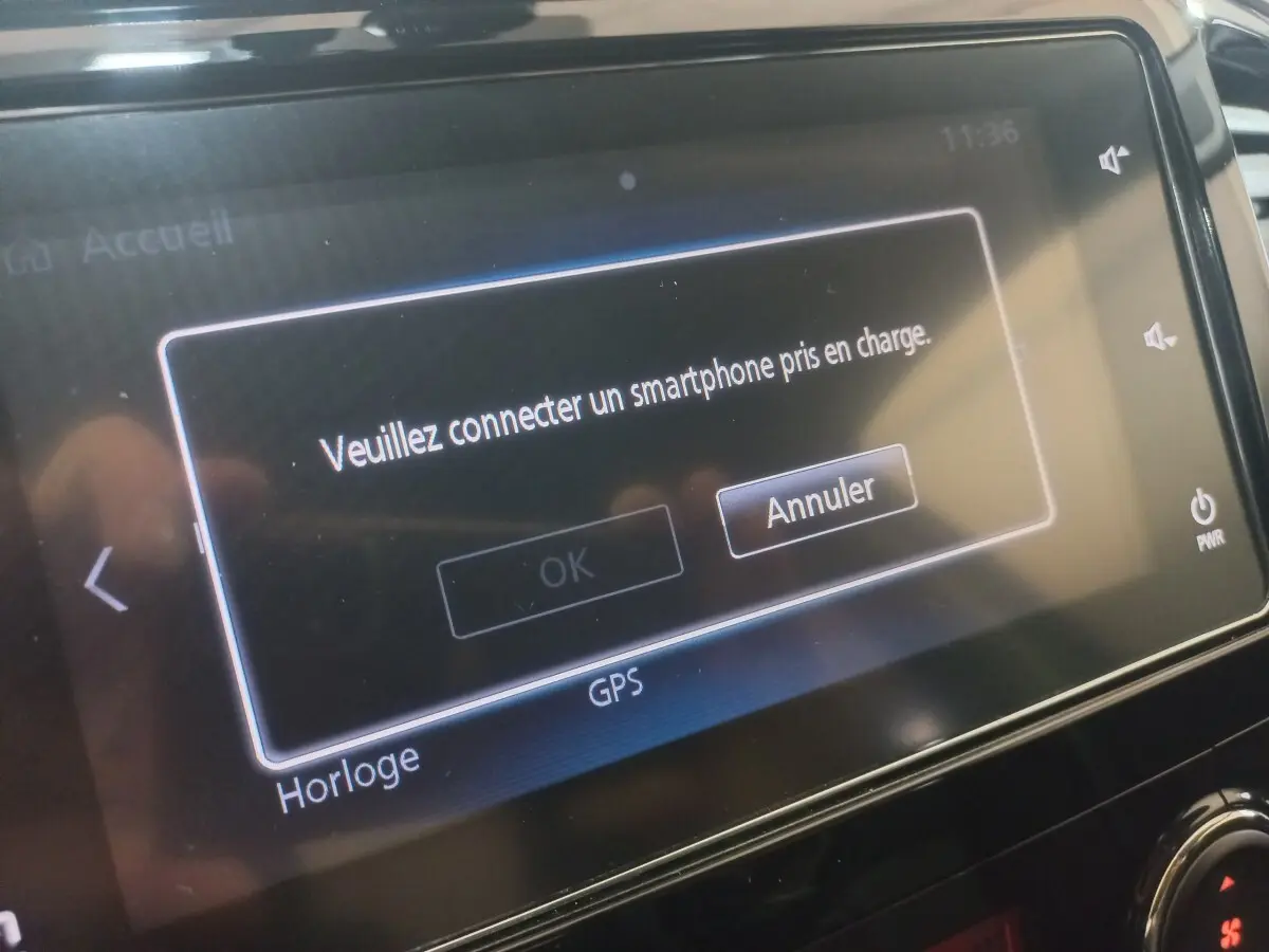 Écran tactile central du Mitsubishi L200 gris foncé affichant un message de connexion smartphone en intérieur véhicule.