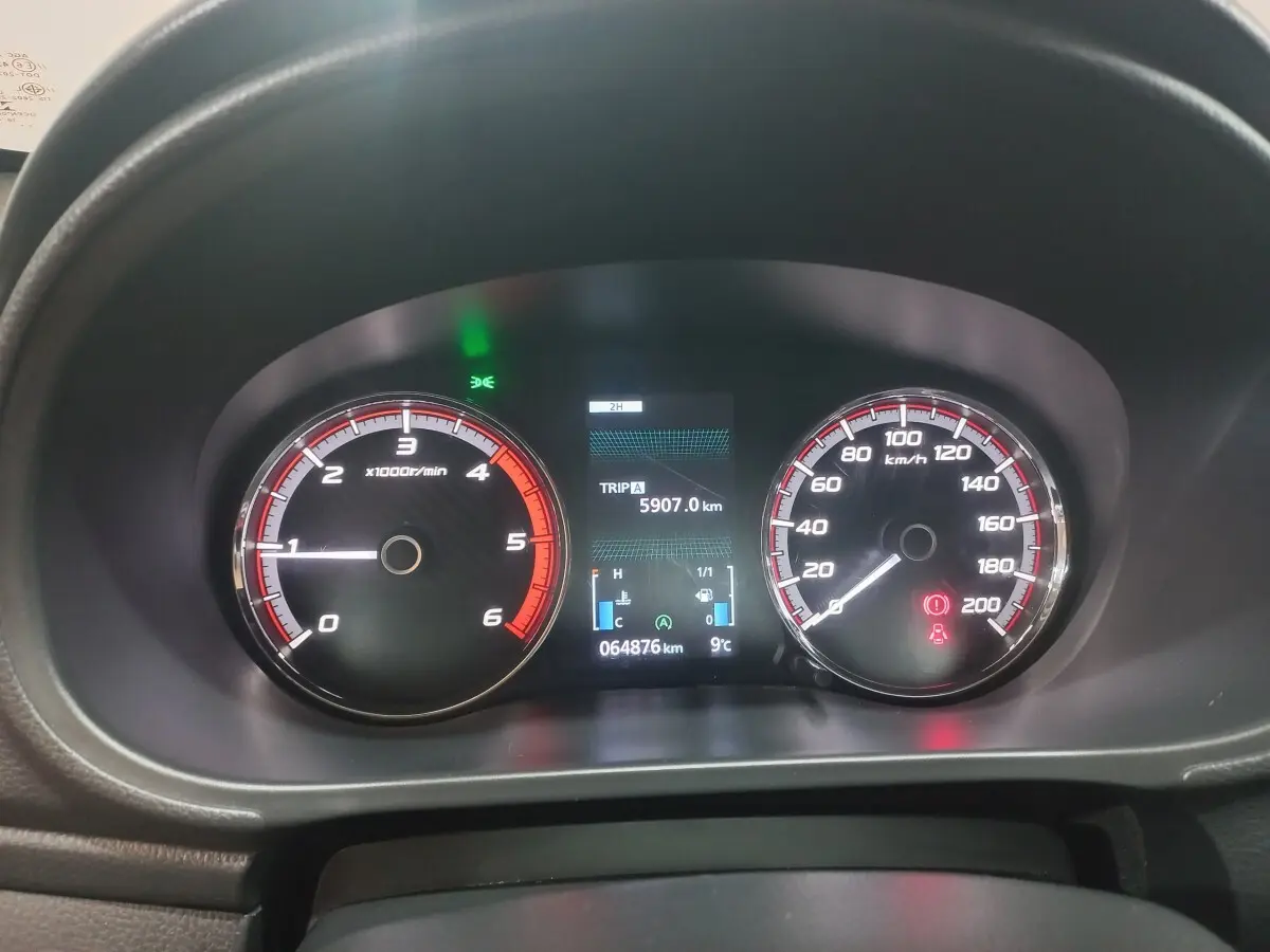 Vue rapprochée du tableau de bord du Mitsubishi L200 gris foncé, affichant compte-tours, vitesse et écran digital.