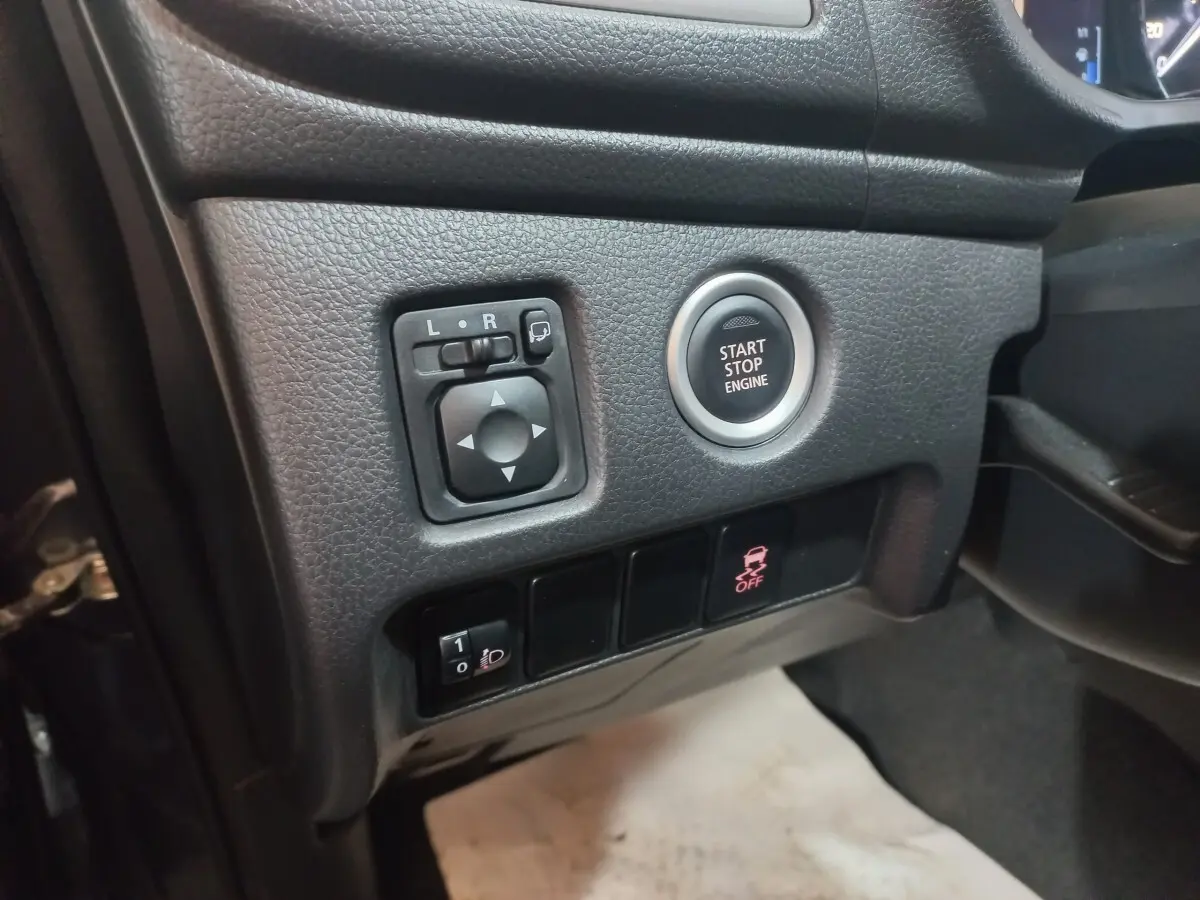 Vue rapprochée côté gauche du tableau de bord gris foncé du Mitsubishi L200 avec bouton Start/Stop et commandes des rétroviseurs.