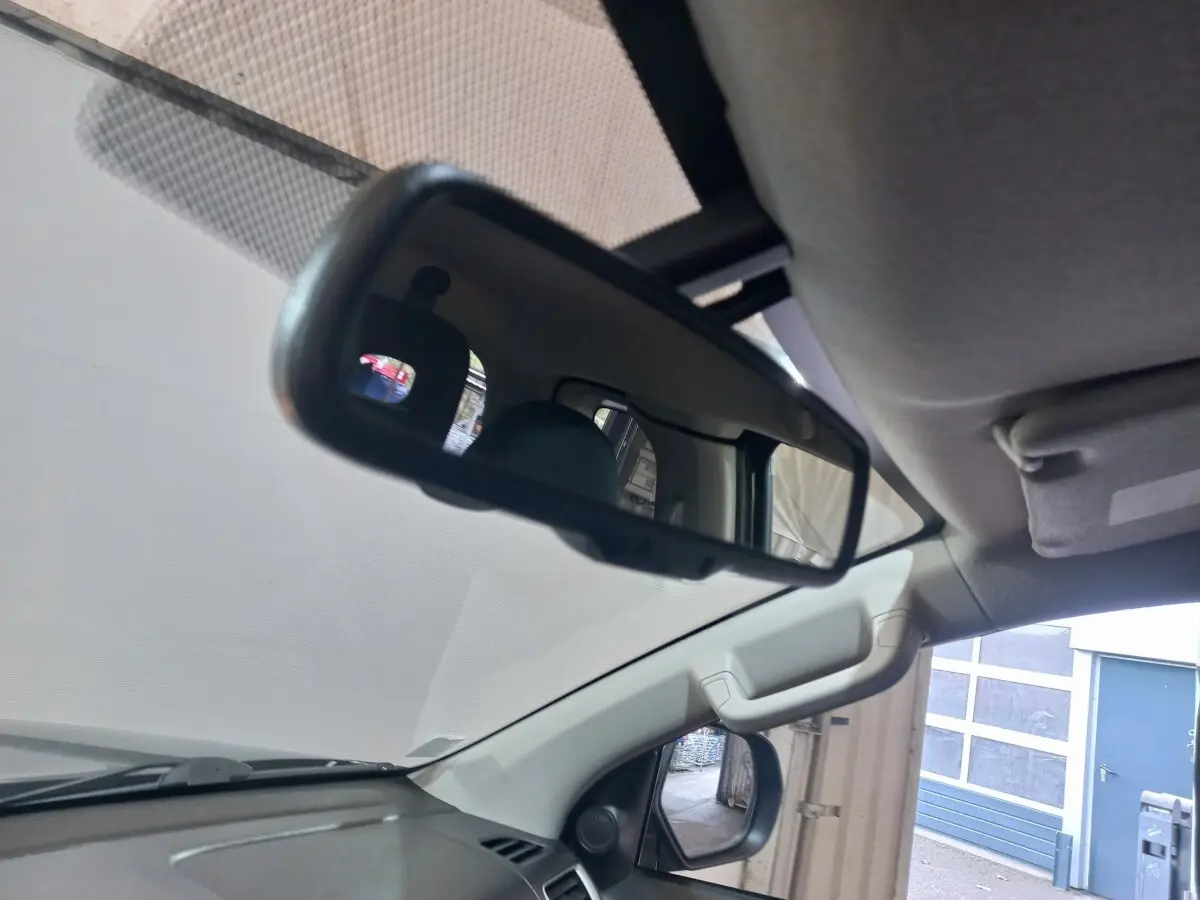 Vue intérieure du rétroviseur central et du pare-brise du Mitsubishi L200 gris foncé, côté conducteur visible.