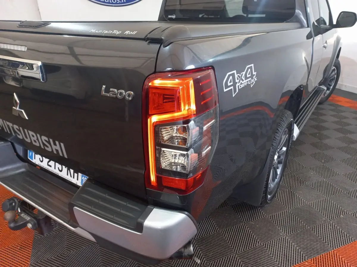 Vue 3/4 arrière droite du pick-up Mitsubishi L200 gris foncé avec feux arrière allumés et logo 4x4 Diff Lock visible.