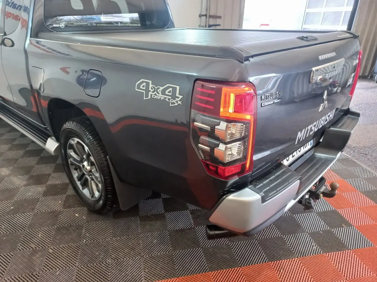 Vue 3/4 arrière droite du Mitsubishi L200 gris foncé avec logo 4x4 Diff Lock et benne fermée.