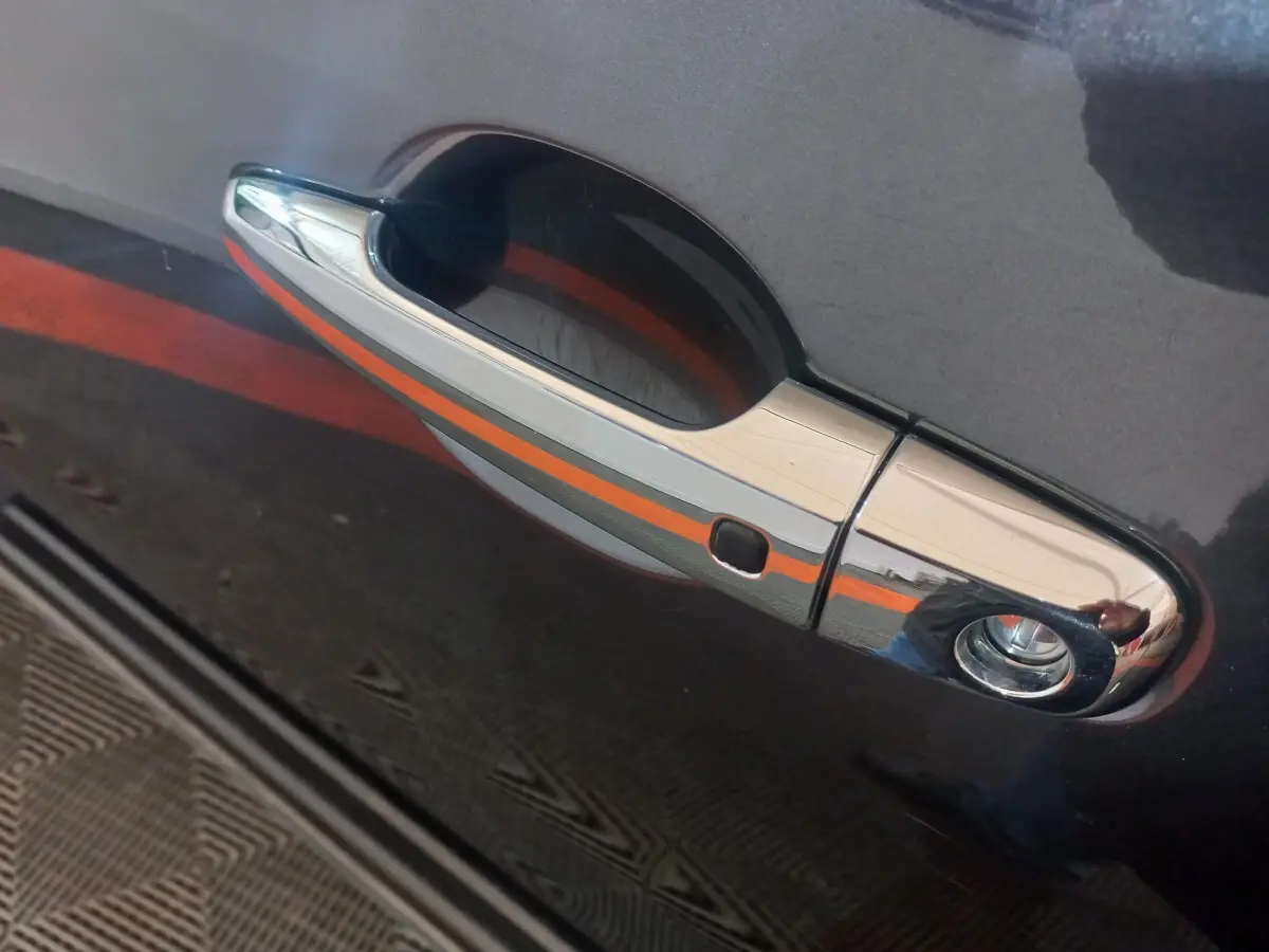 Poignée de porte chromée sur la portière gris foncé d’un Mitsubishi L200, vue en gros plan côté gauche.