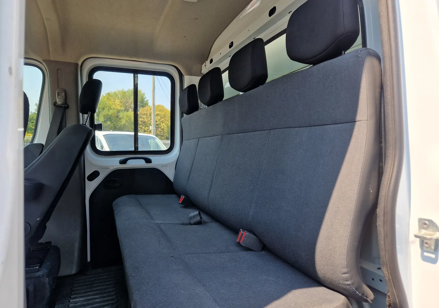 Vue intérieure côté droit du Renault Master blanc, montrant la banquette arrière noire avec trois appuie-têtes.