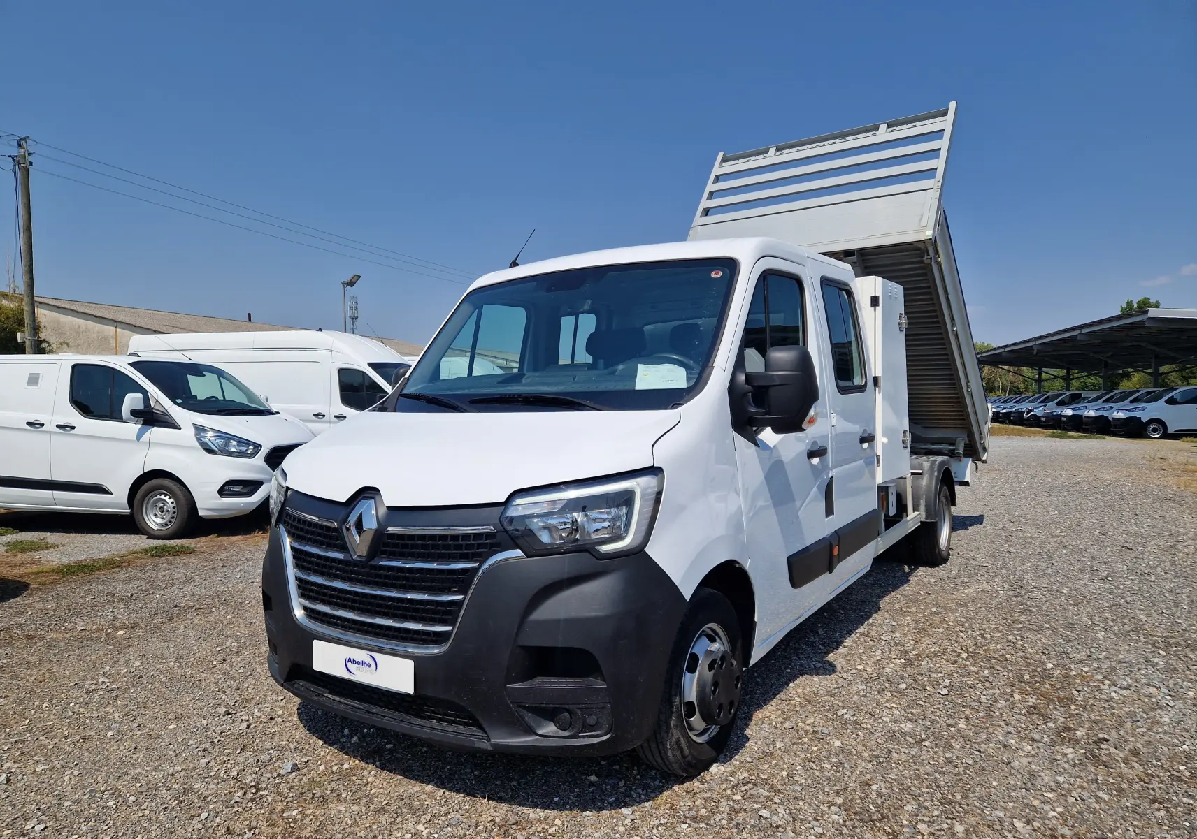 Renault Master Chassis double cabine blanc vu en 3/4 avant droit avec benne alu relevée et coffre latéral.