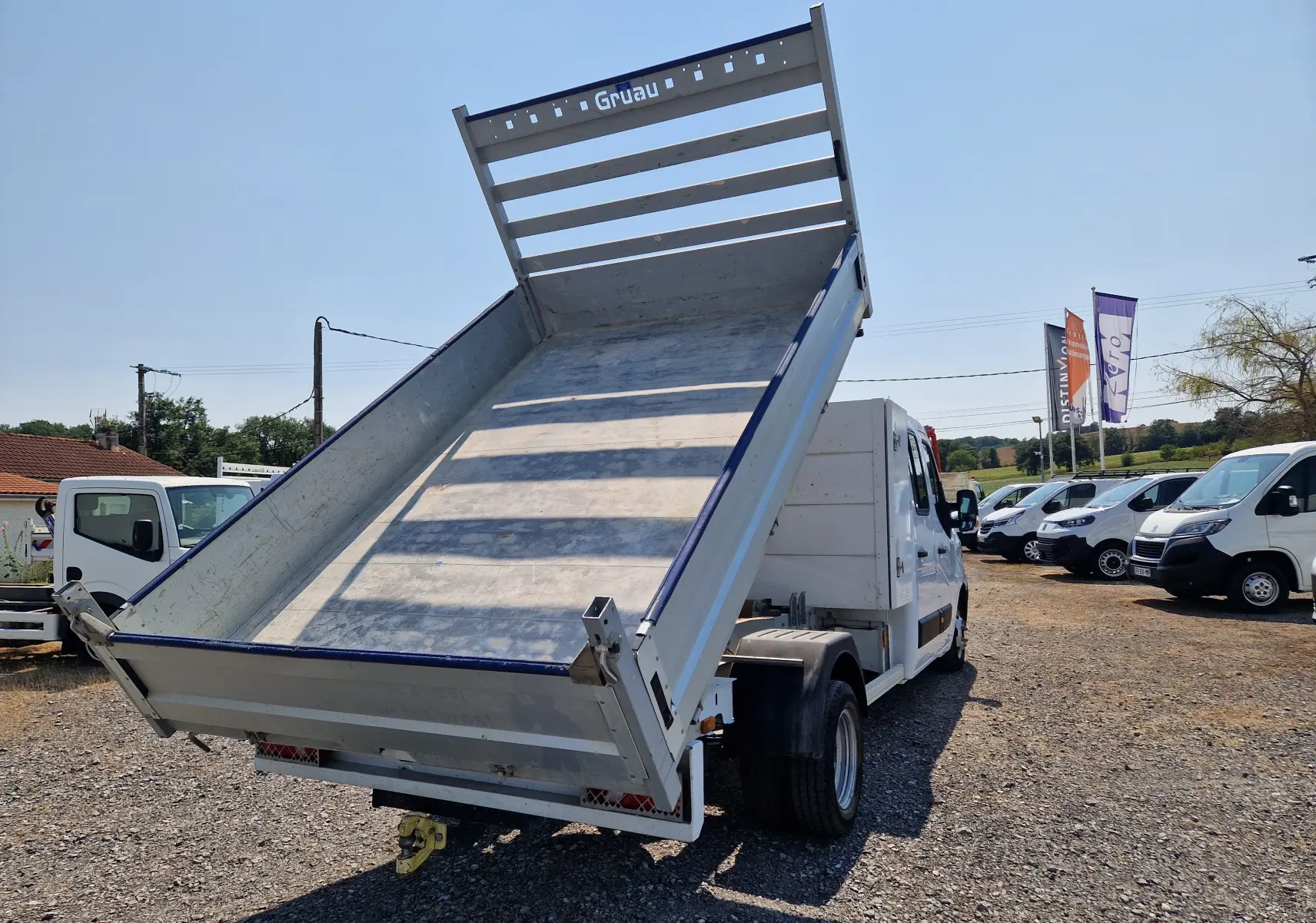 Renault Master Chassis double cabine blanc vu 3/4 arrière avec benne aluminium relevée et coffre intégré.