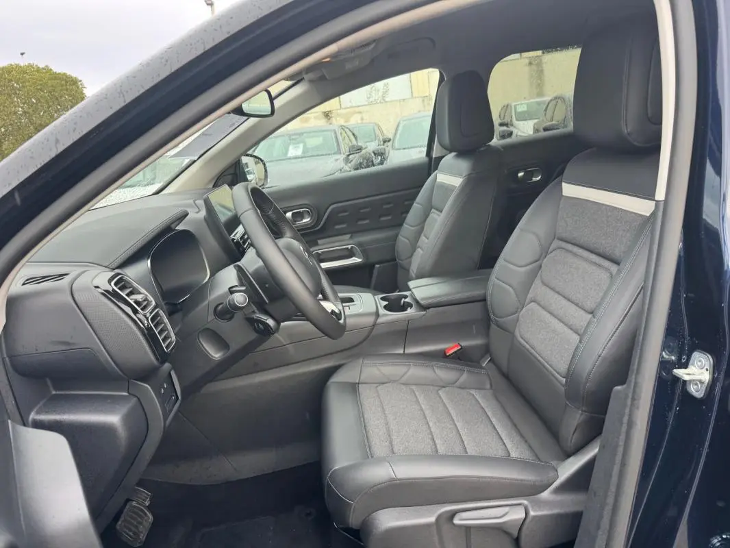 Vue intérieure côté conducteur du Citroën C5 Aircross bleu foncé 2024, sièges en cuir et tissu gris avec tableau de bord moderne.