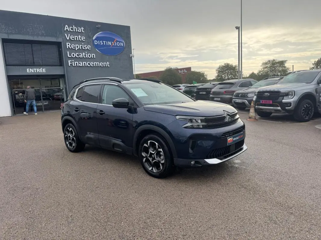 Citroën C5 Aircross hybride bleu foncé vue 3/4 avant droit avec barres de toit et jantes alliage 18 pouces.