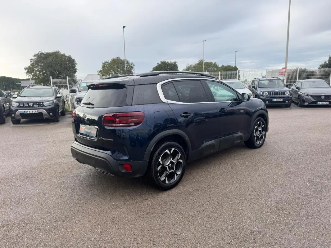 Citroën C5 Aircross bleu foncé vue 3/4 arrière droit avec barres de toit et jantes alliage 18 pouces.