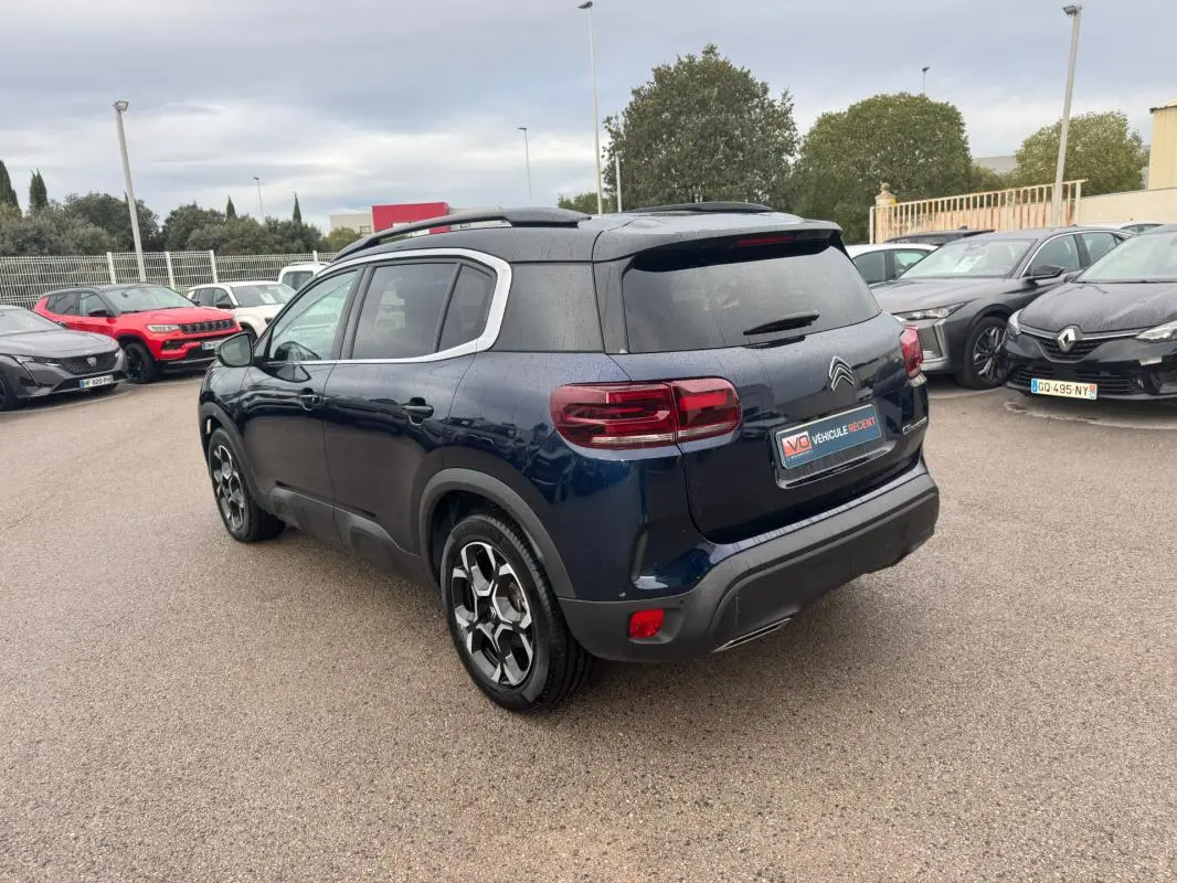 Vue 3/4 arrière droite d’un Citroën C5 Aircross bleu foncé avec barres de toit et jantes alliage 18 pouces.