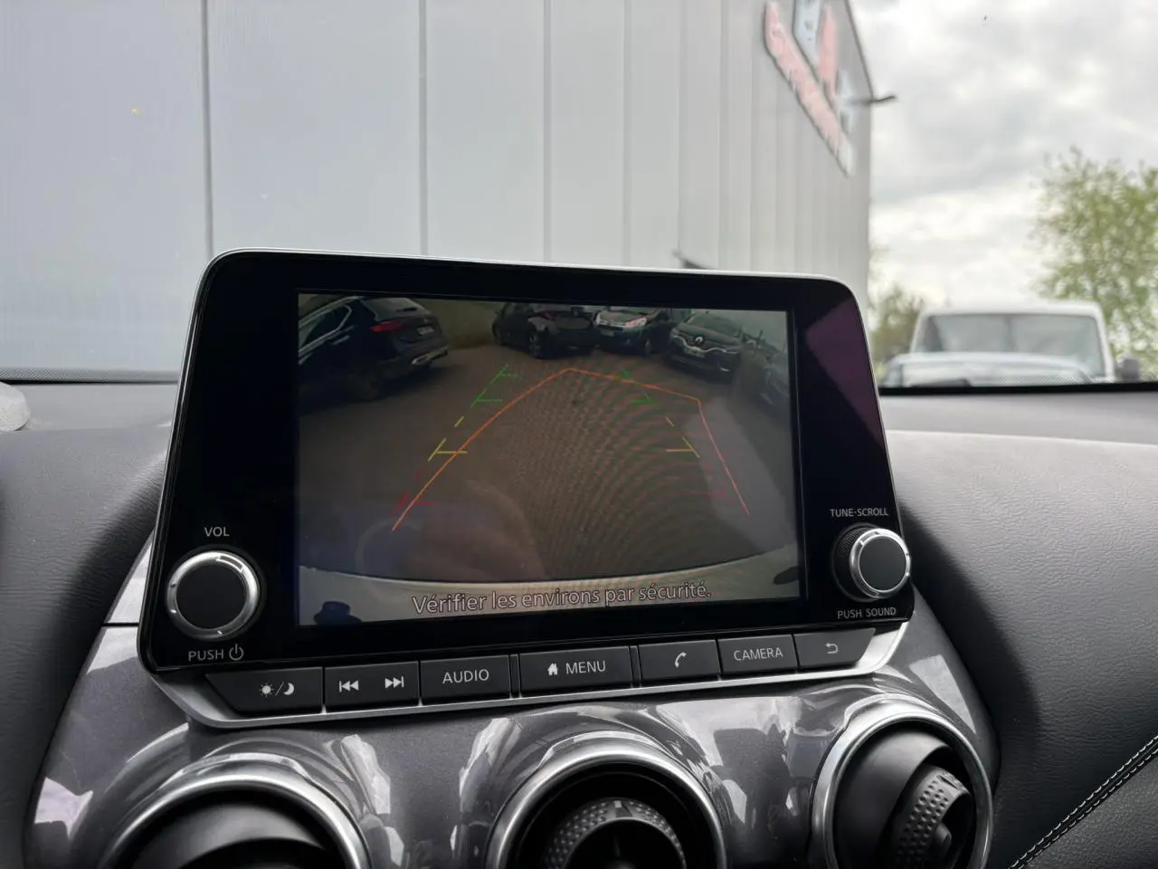 Écran central du Nissan Juke 2023 montrant la caméra de recul avec lignes de guidage colorées.