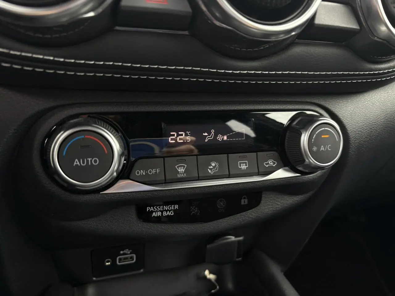 Gros plan sur la commande de climatisation automatique du Nissan Juke blanc perle 2023 avec affichage digital à 22,5°C.