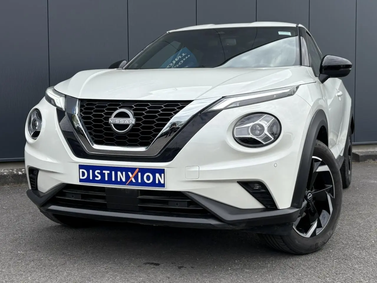 Nissan Juke blanc perle vu de face droite, avec calandre noire et jantes alliage noires distinctives.
