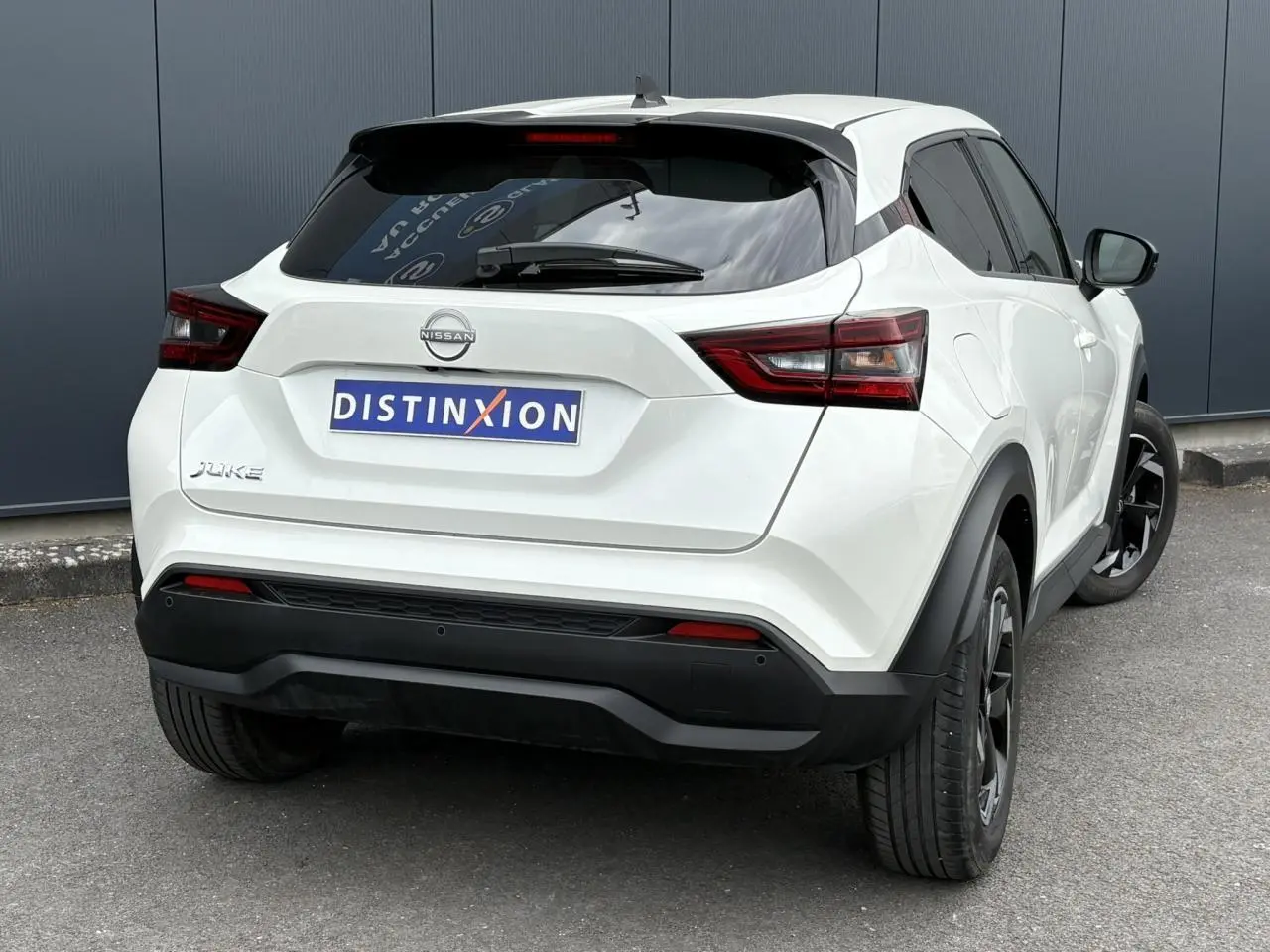 Vue 3/4 arrière droite du Nissan Juke blanc perle 2023 avec feux LED et jantes alliage noires.