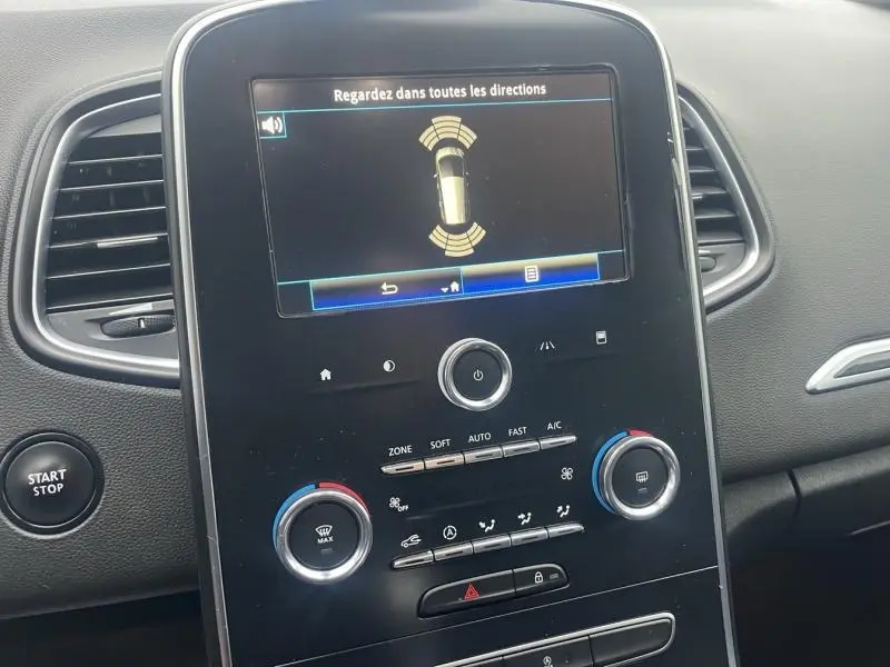 Tableau de bord noir du Renault Grand Scenic bleu Cosmos 2022 avec écran tactile affichant l'aide au stationnement.