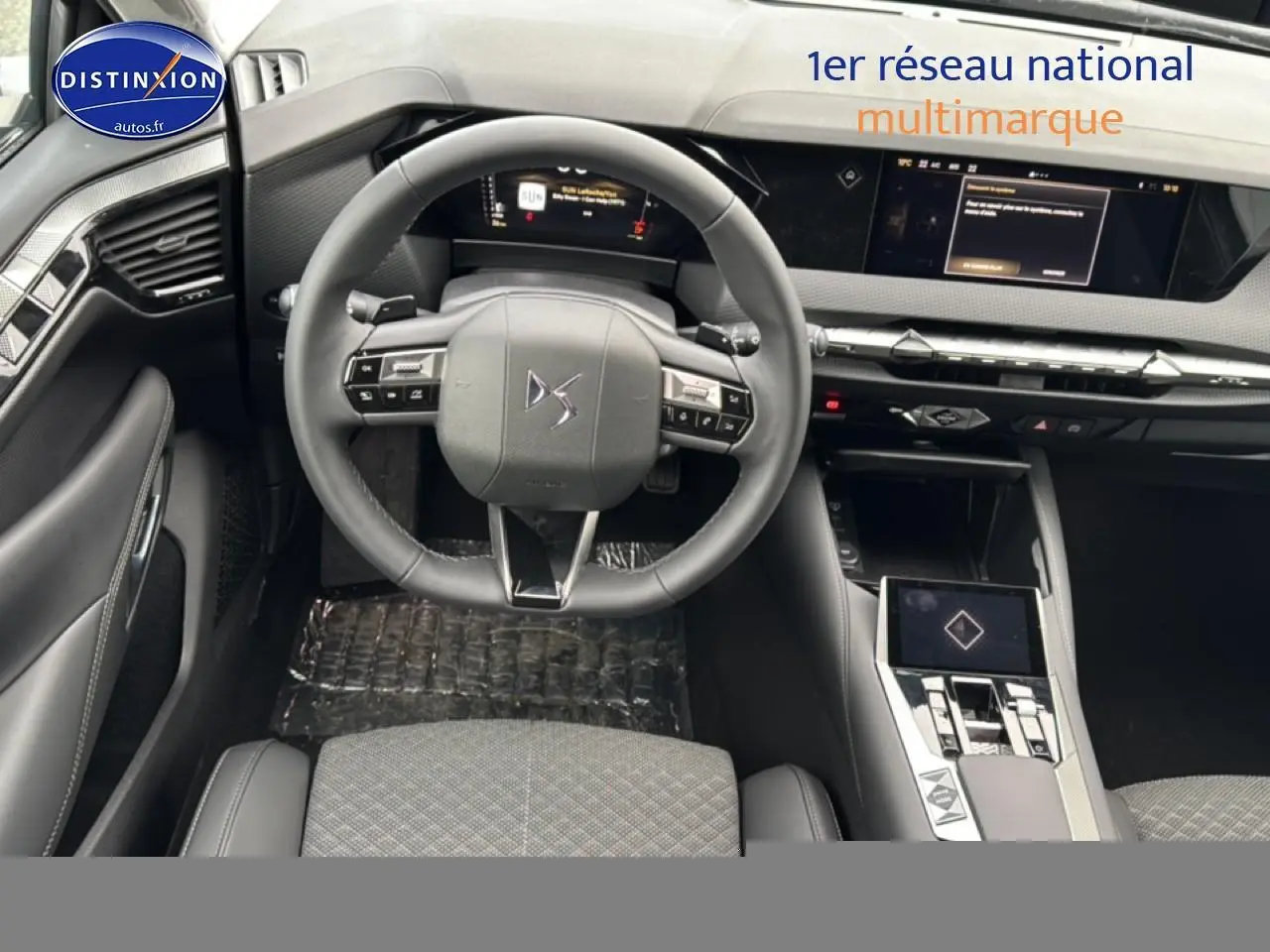 Vue intérieure centrée sur le volant cuir et tableau de bord numérique du DS4 Hybride 145 gris platinium 2024.