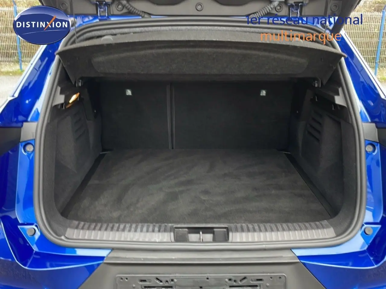 Coffre ouvert vu de l'arrière d'une Renault Symbioz bleu iron metal, montrant un espace de chargement propre et spacieux.