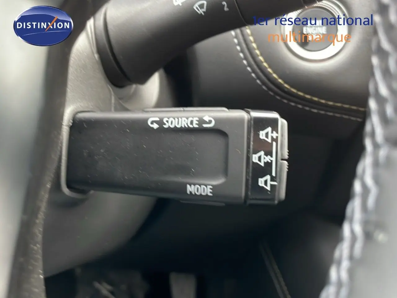 Gros plan sur la commande au volant du Renault Symbioz bleu iron metal, avec boutons source et mode visibles.