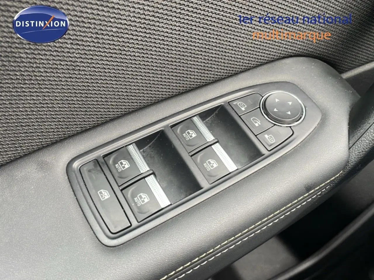 Gros plan sur les commandes des vitres électriques côté gauche d’un Renault Symbioz bleu Iron Metal, finition 2025.