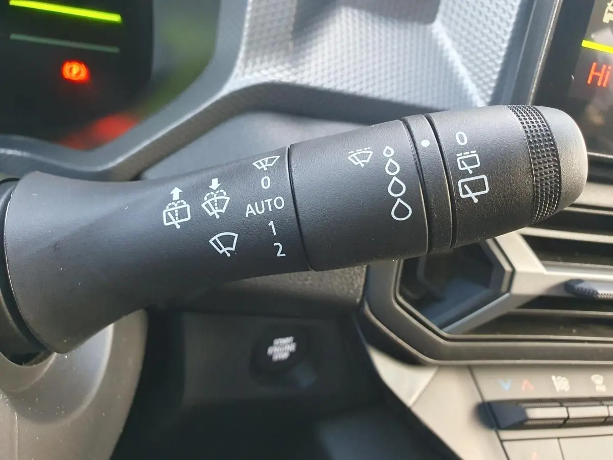 Gros plan sur la commande d’essuie-glace du tableau de bord du Dacia Duster 2026 vert cèdre, intérieur noir.