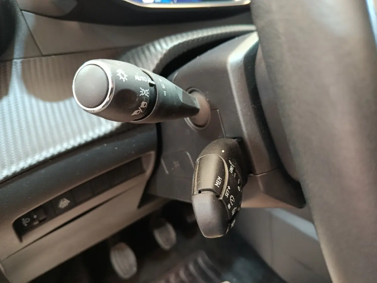 Gros plan sur les commandes au volant d’une Peugeot 208 PureTech 100 S&S Allure Business, intérieur noir.