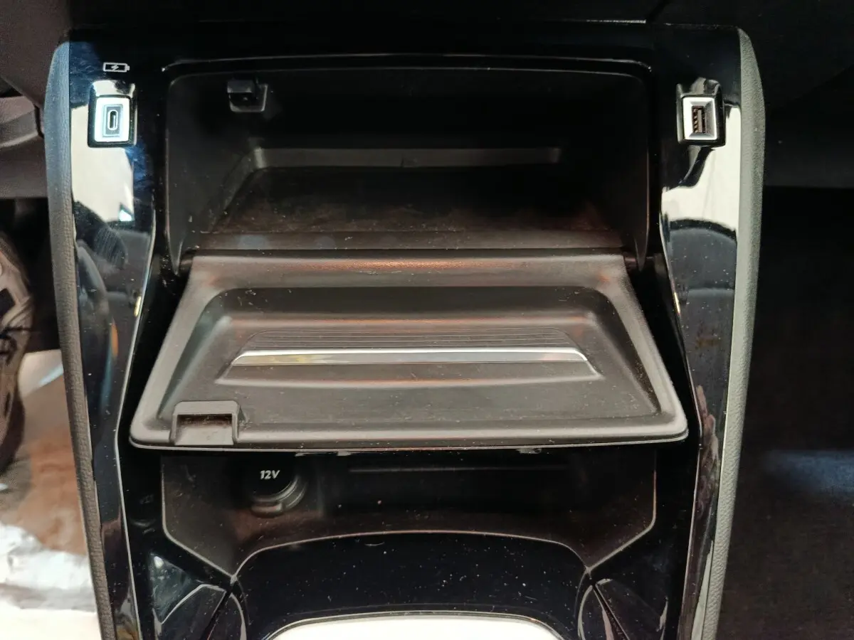Vue rapprochée de la console centrale noire de la Peugeot 208 avec compartiment ouvert et ports USB visibles.