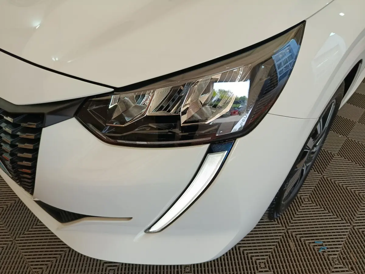 Gros plan sur le phare avant droit blanc de la Peugeot 208 PureTech 100 S&S Allure Business 2021.