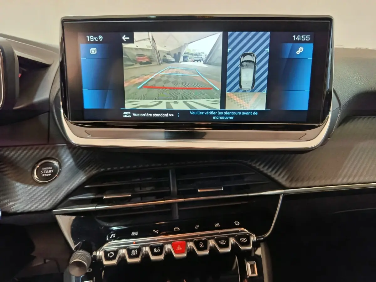 Vue rapprochée de l’écran tactile central affichant la caméra de recul dans l’habitacle noir d’une Peugeot 208 blanche.