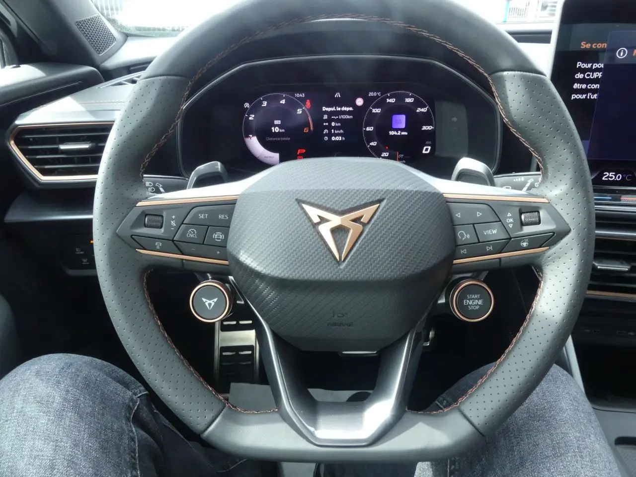 Vue rapprochée du volant perforé noir avec surpiqûres cuivrées et tableau de bord digital du CUPRA Formentor gris magnétique 2025.