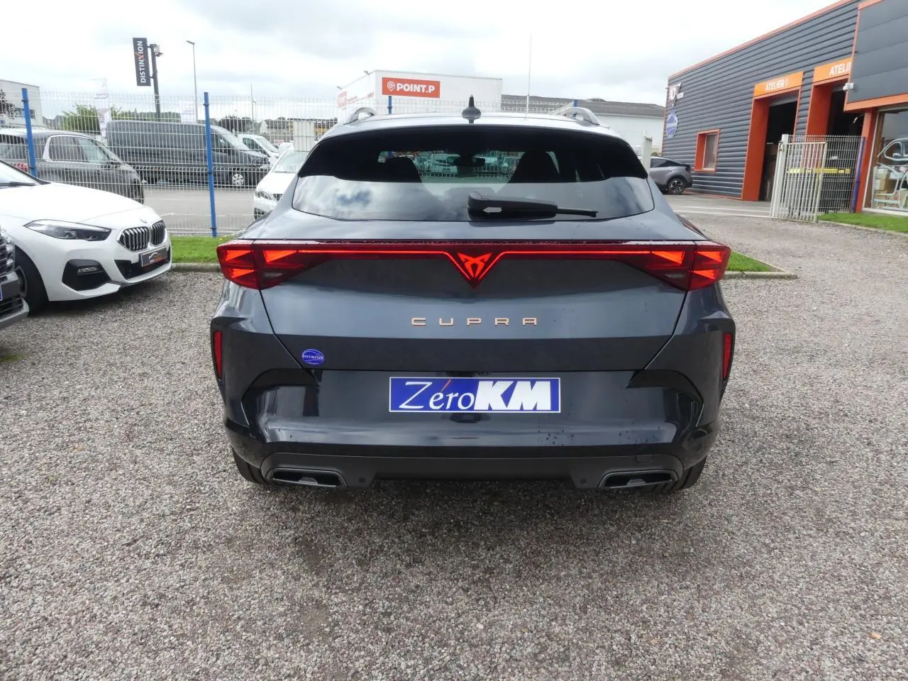 Vue arrière d'un CUPRA Formentor gris magnétique avec signature lumineuse Tri-LED et double sortie d'échappement noire.