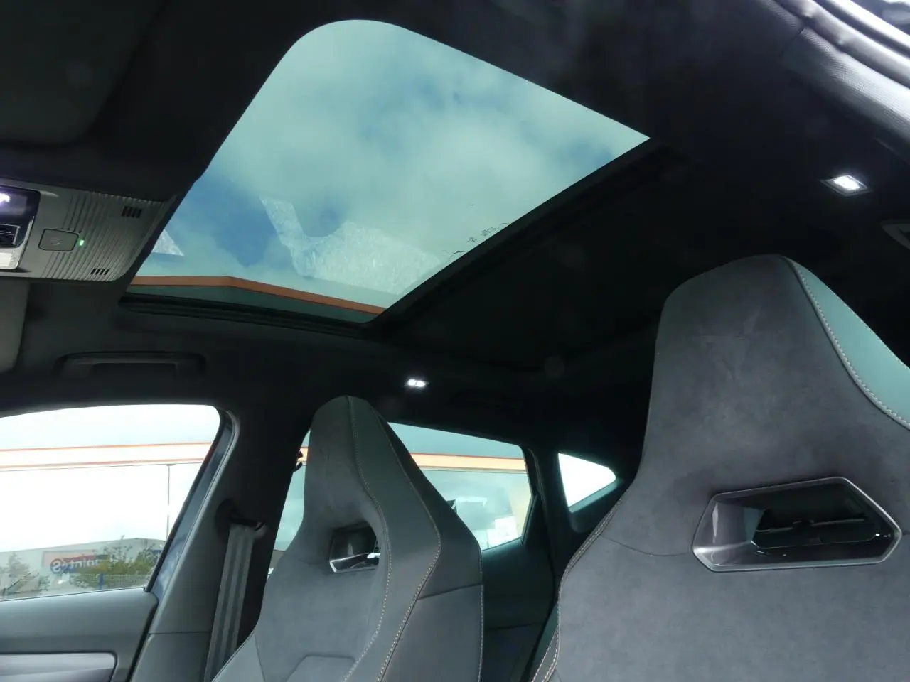 Intérieur du Cupra Formentor vu côté conducteur, sièges baquets suédine noire avec surpiqûres cuivrées et toit panoramique.