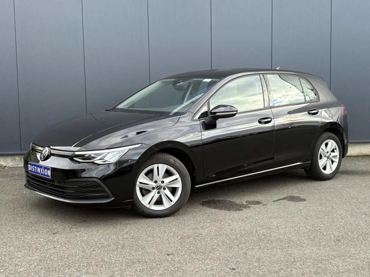 Volkswagen Golf VIII 2.0 TDI noire vue en 3/4 avant droit sur un parking ensoleillé.