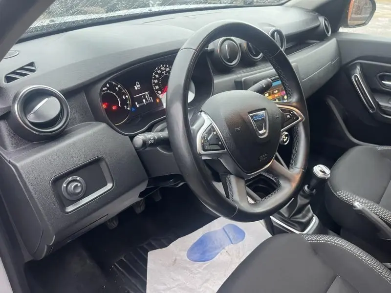 Vue intérieure côté conducteur du Dacia Duster 2021 avec volant multifonction et tableau de bord noir.